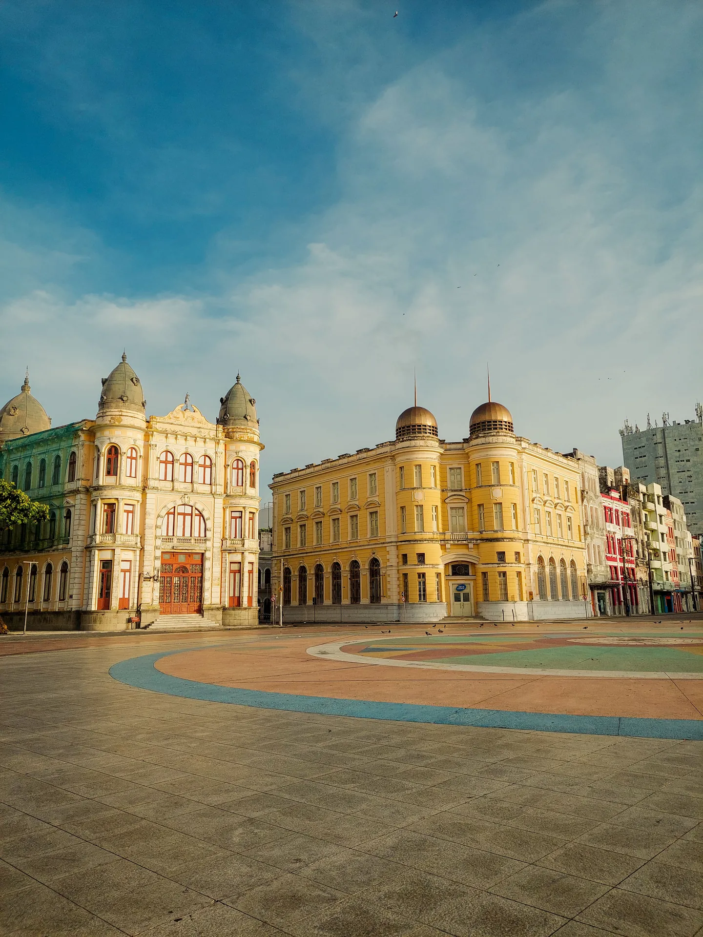 Praça do Marco Zero no Recife Antigo, com os casarões amarelos e o piso colorido vazio na luz da manhã